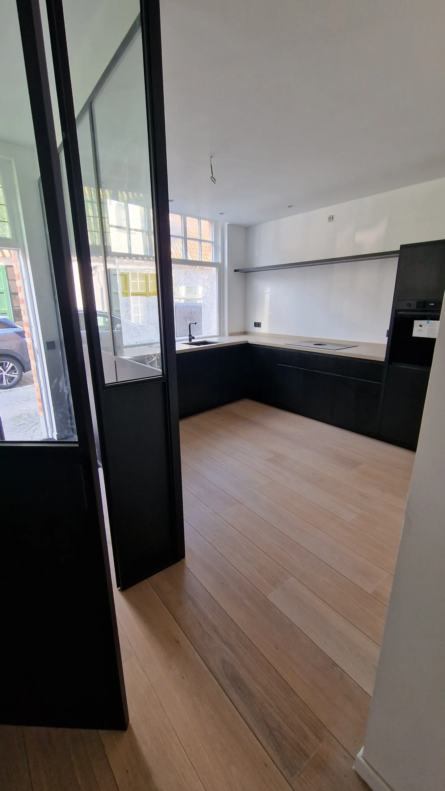 Detail stalen warmteslot – strak schrijnwerk in zwart gepoederlakt staal Stalen inkom met deur en ramen