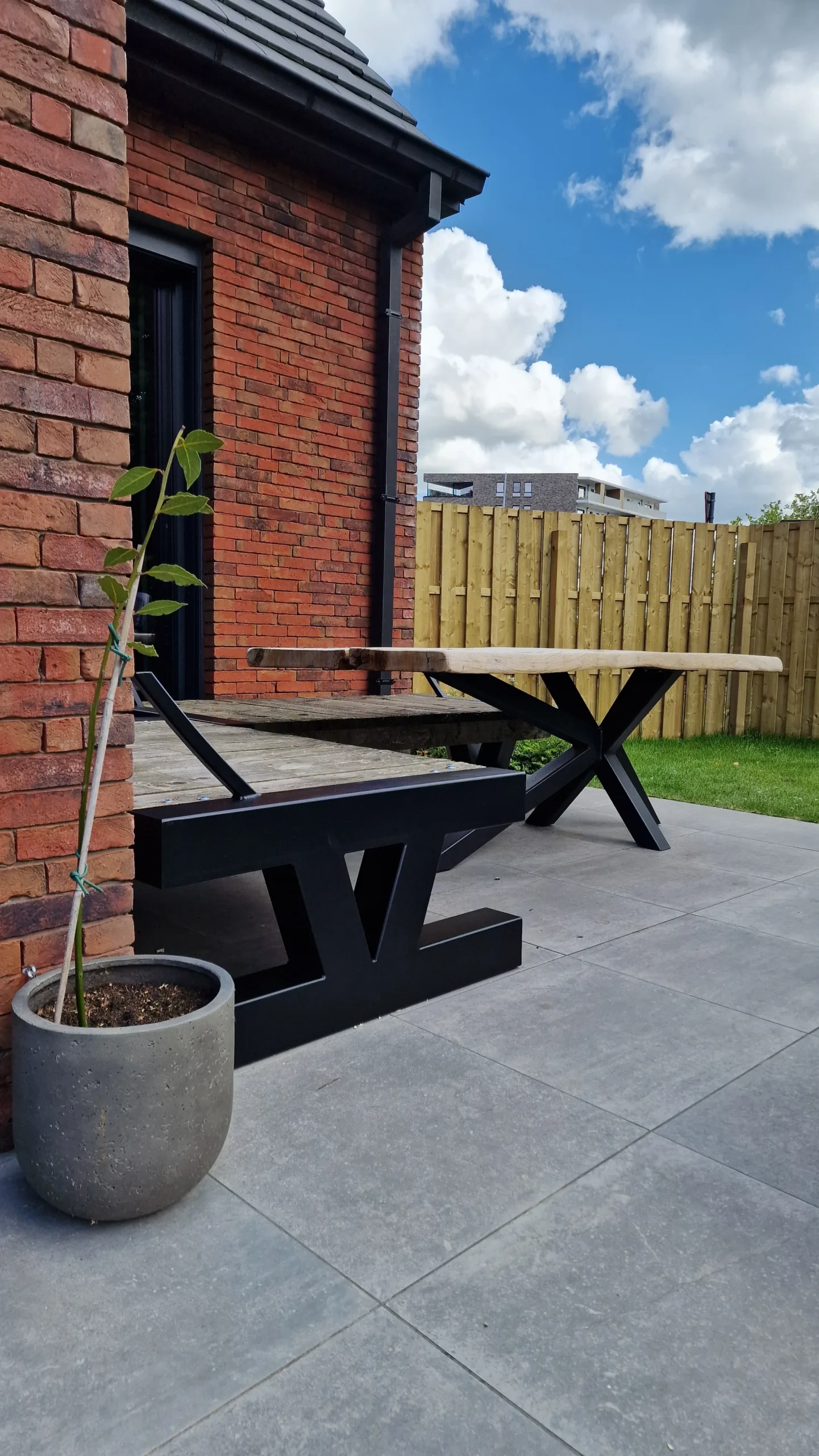 Tafelpoot met kruiselings design – strak staalwerk voor buitengebruik Detail van op maat gemaakte stalen tafelpoot met kruiselings ontwerp, zwart gepoederlakt