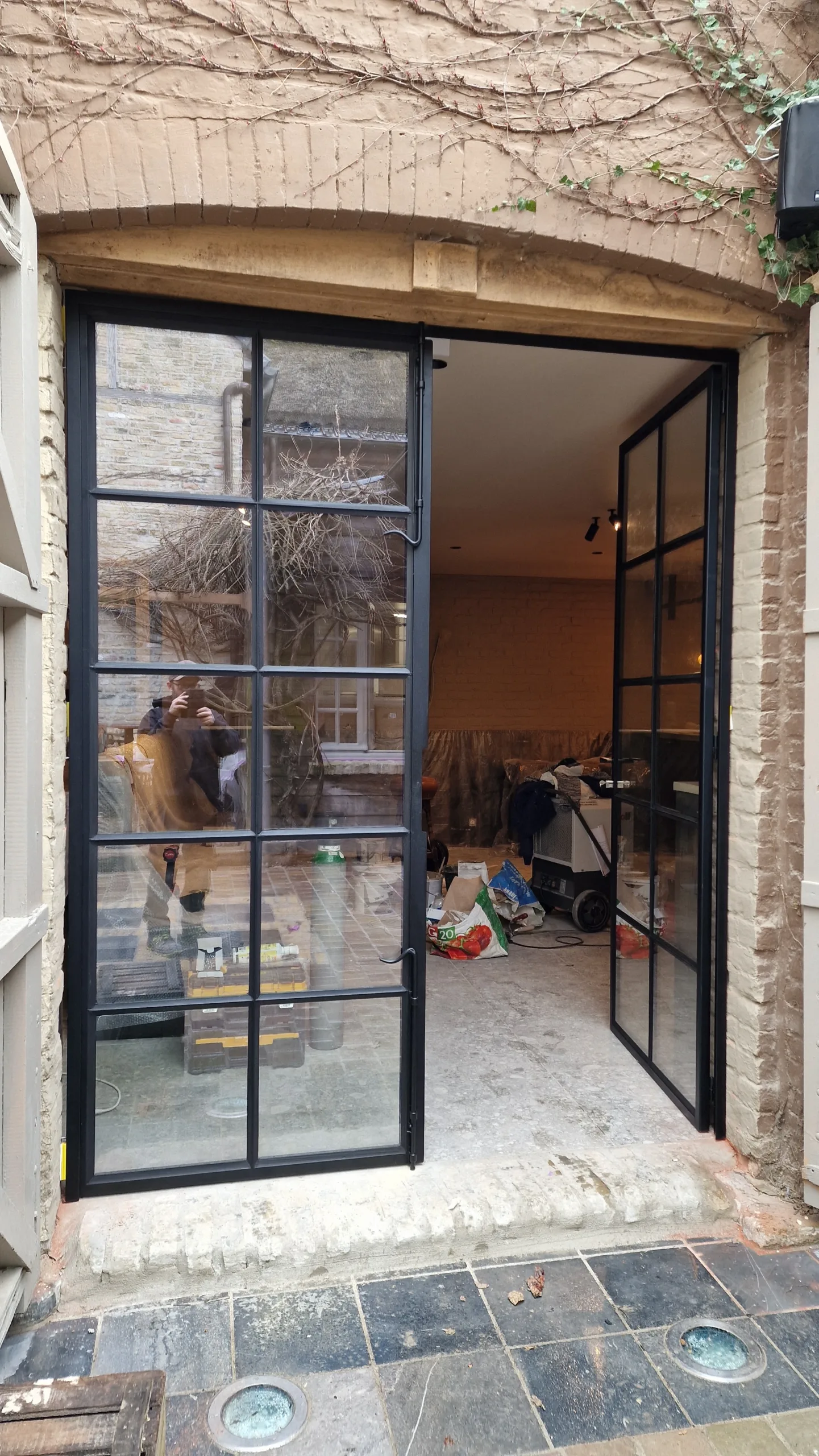 Stalen deur met karakter – roedeverdeling in vierkante vlakken Dubbele stalen deur met vierkante roedeverdeling, geplaatst in een sfeervol interieur