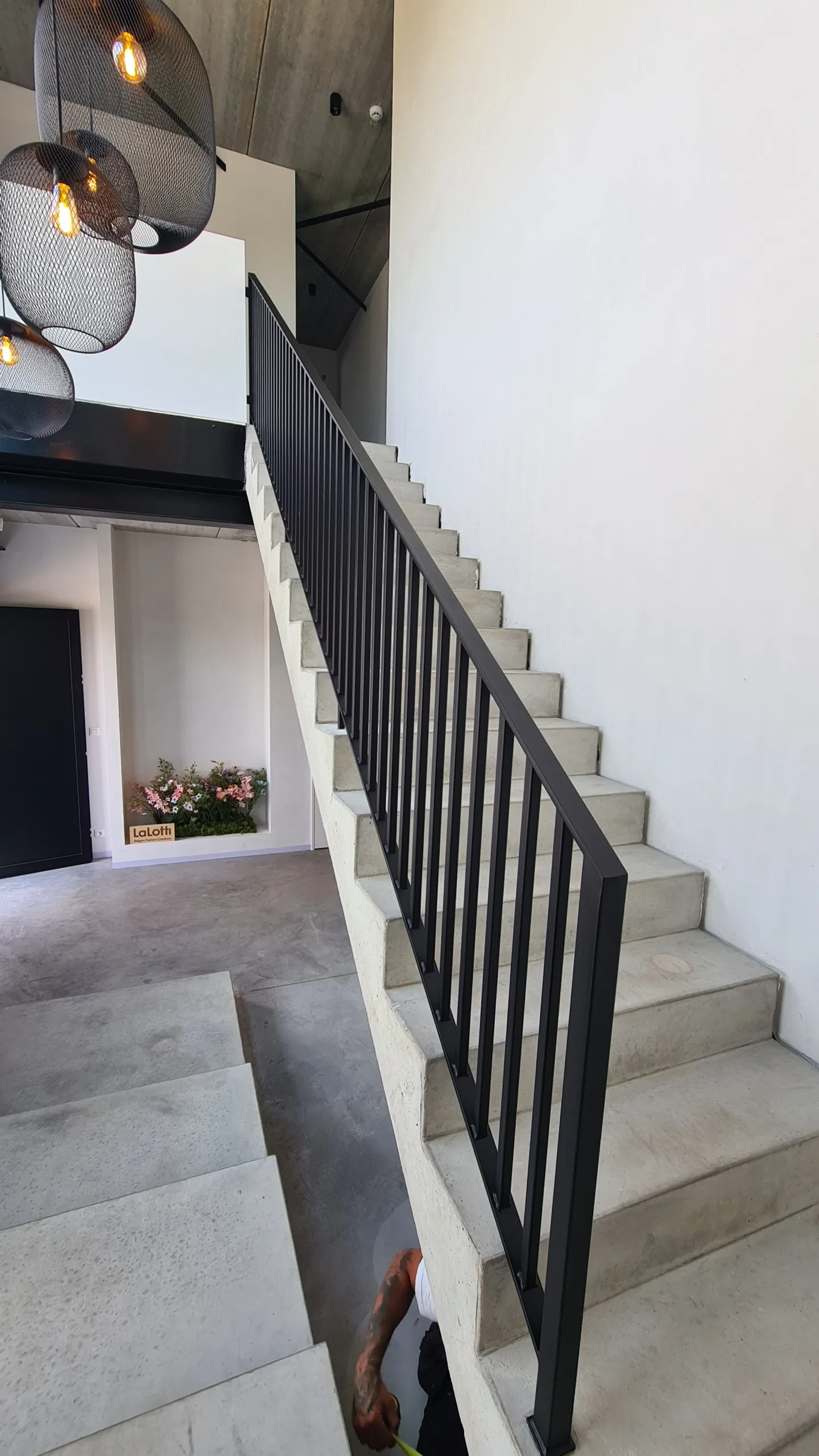 Moderne stalen trapleuning – zwart gepoederlakt op betonnen trap Strakke zwarte stalen trapleuning op een betonnen trap, vervaardigd door JVH Welding