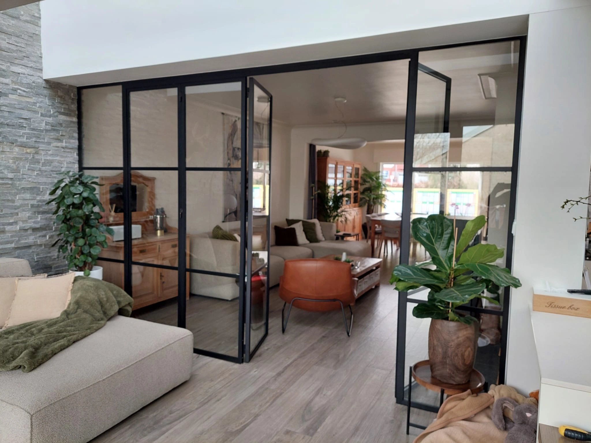 Binnenvouwdeuren in staal, half geopend, met fijne verdelingen en matte poederlak.